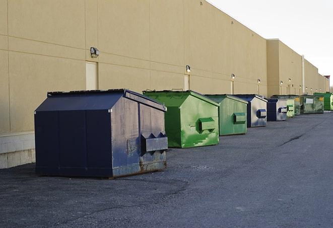 a row of yellow and blue dumpsters at a construction site in Comstock Park